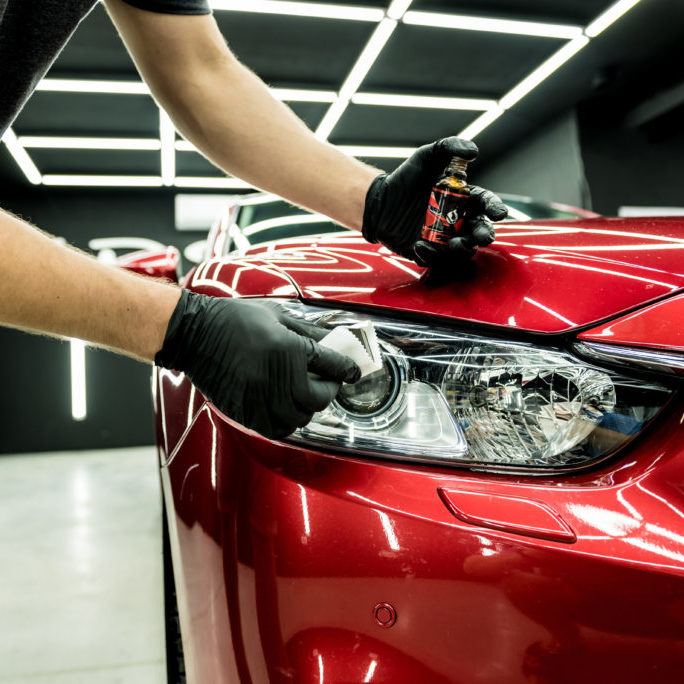 Car service worker applying nano coating on a car detail